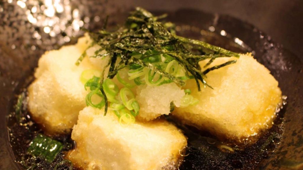 かつお出汁に浸かった美味しそうな揚げ出し豆腐(ネギ、大根おろし、刻み海苔のトッピング)