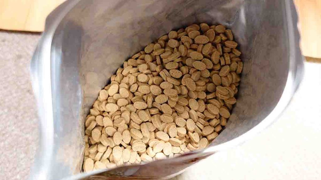 開封した「うまか」のドッグフード袋の中身。薄茶色で楕円形の粒がぎっしりと詰まっている様子。