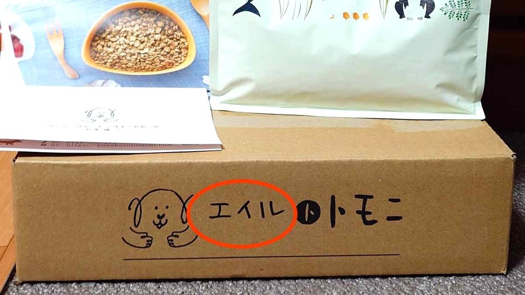 「エイル」と名前が手書きされた段ボール側面の「(空白)トトモニ」のロゴ